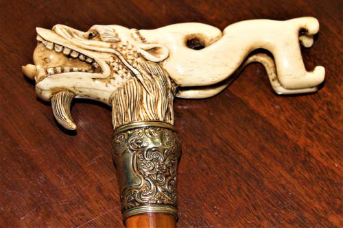 A finely carved large and chunky Chinese bone walking stick depicting a dragon with a loose ball in its mouth (1 of 6)