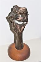 A bronze masquerade theatrical mask being held by a hand (7 of 9) A bronze masquerade theatrical mask being held by a hand (7 of 9)